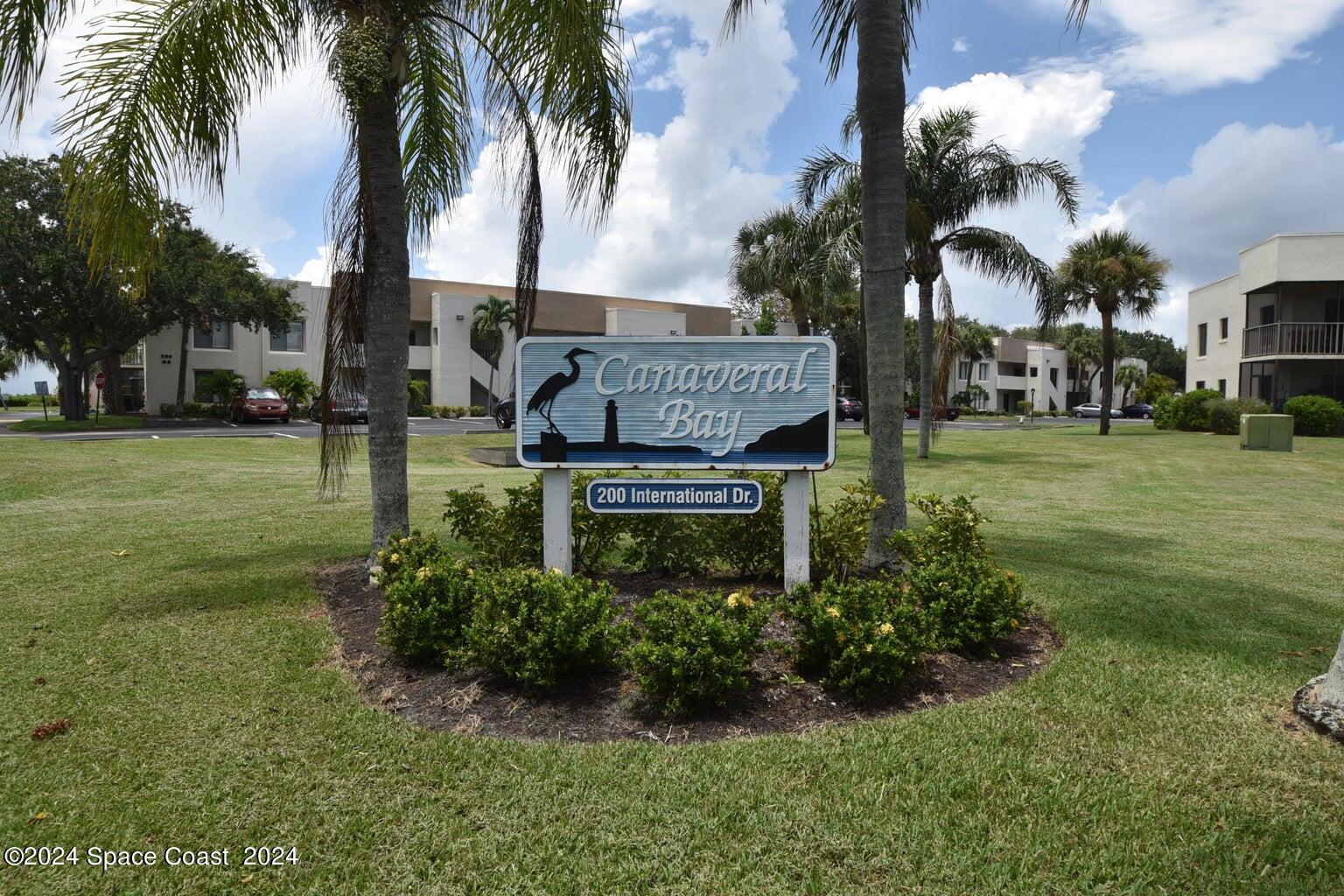 a view of a park that has a sign board large tree