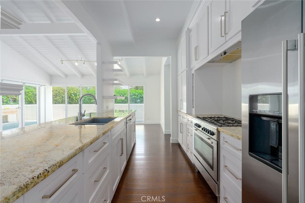 a kitchen with granite countertop a sink stainless steel appliances and window