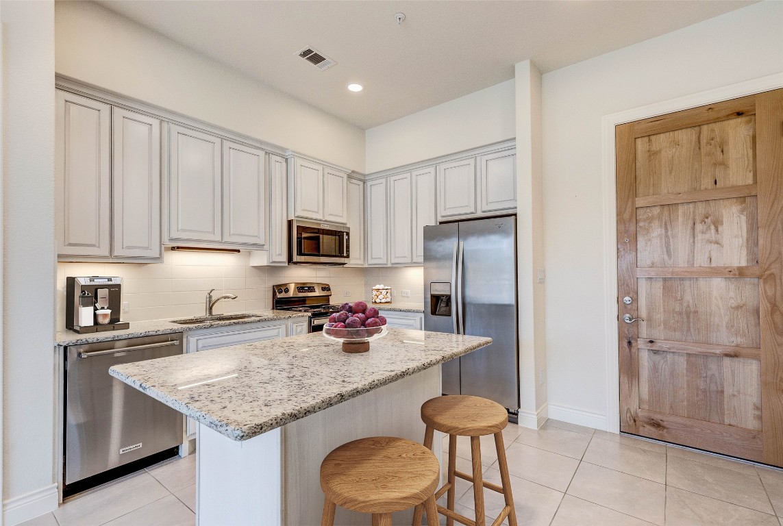 a kitchen with stainless steel appliances granite countertop a refrigerator and a stove top oven