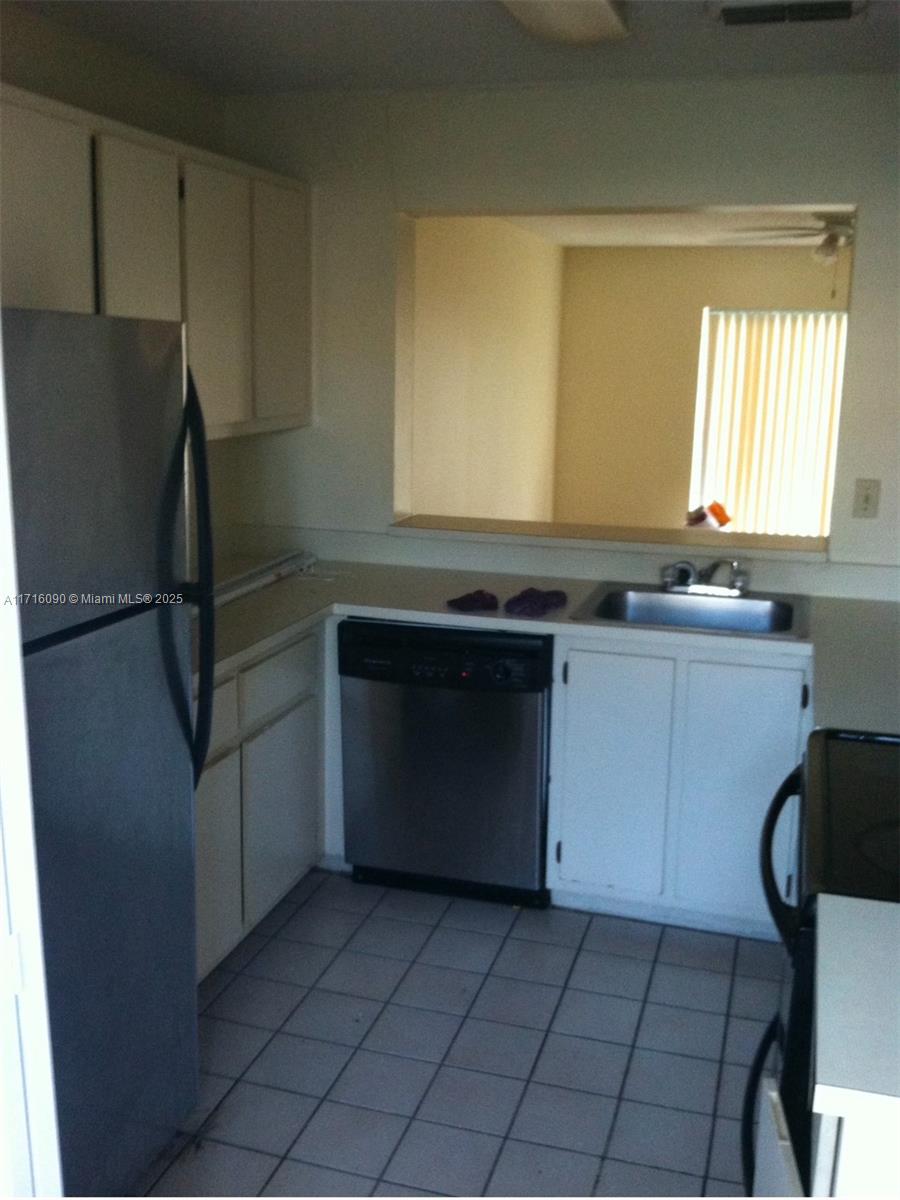 a kitchen with a sink a refrigerator and cabinets