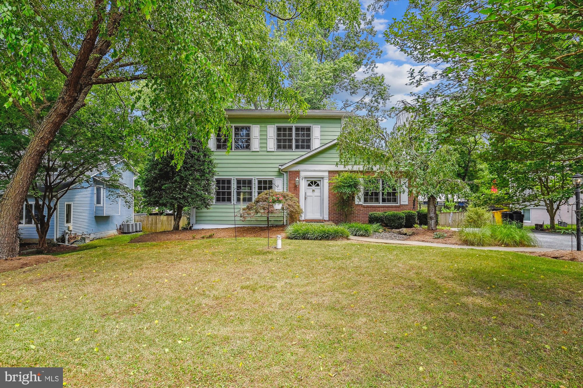 a front view of a house with a garden and trees