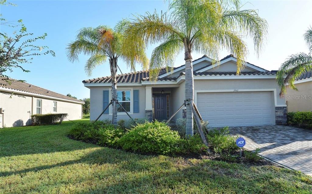 a view of a house with a yard and palm trees