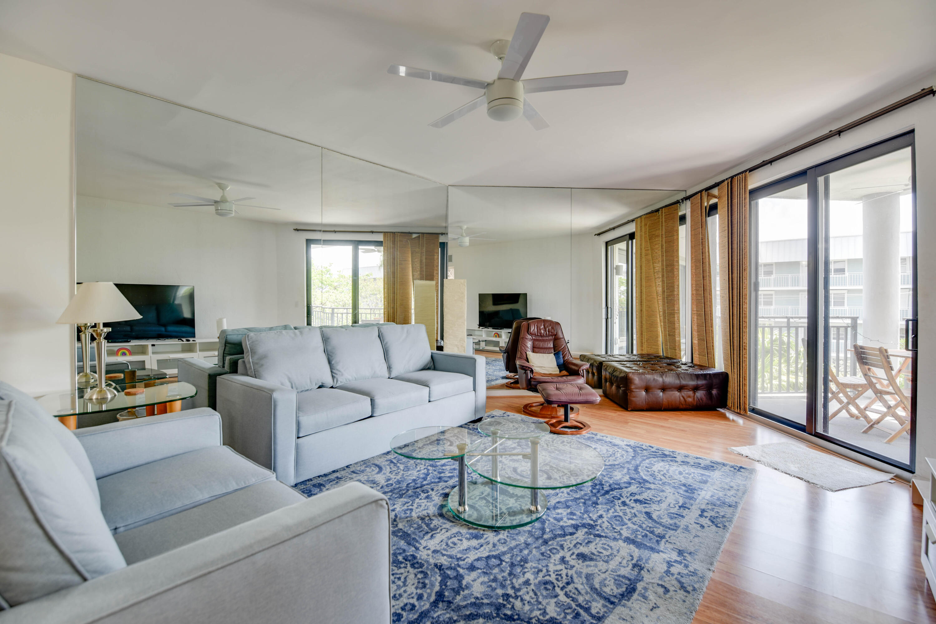 a living room with furniture floor to ceiling window and a flat screen tv