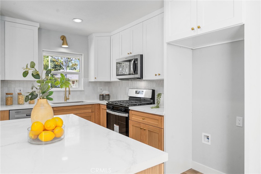 a kitchen with stainless steel appliances a stove a sink cabinets and a window