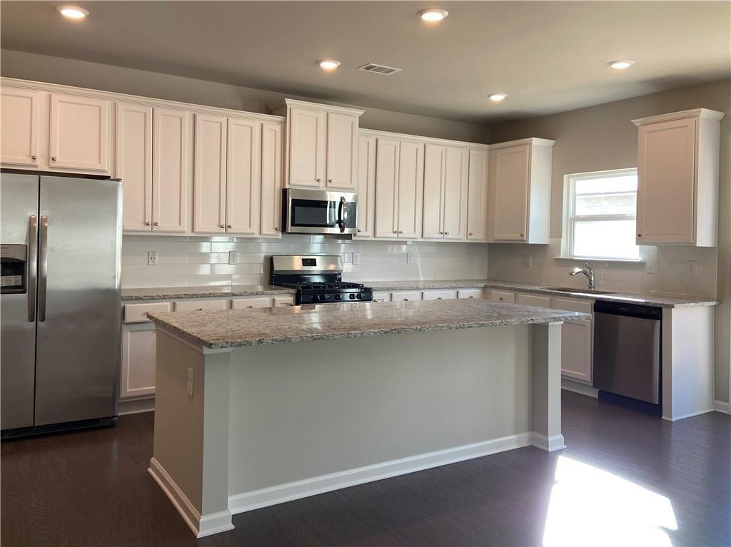 a kitchen with kitchen island granite countertop a sink stainless steel appliances and cabinets