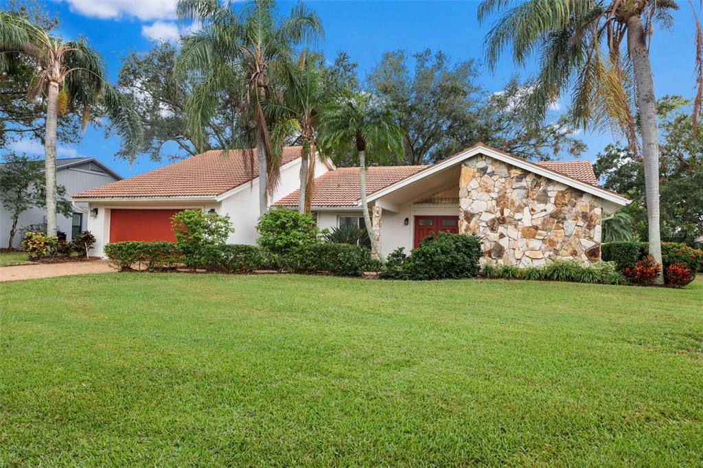 a view of a house with a yard and palm trees