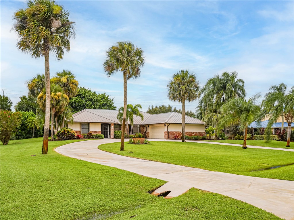 a front view of a house with a yard and palm trees