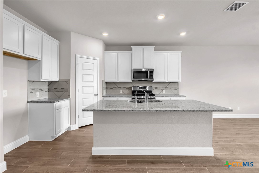 a kitchen with kitchen island granite countertop a sink cabinets and stainless steel appliances