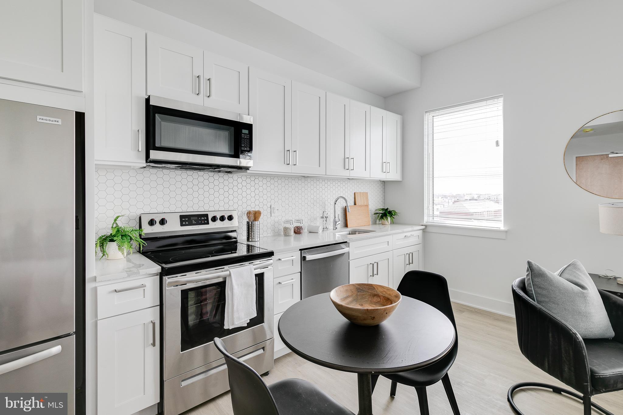 a kitchen with stainless steel appliances a white table and chairs in it