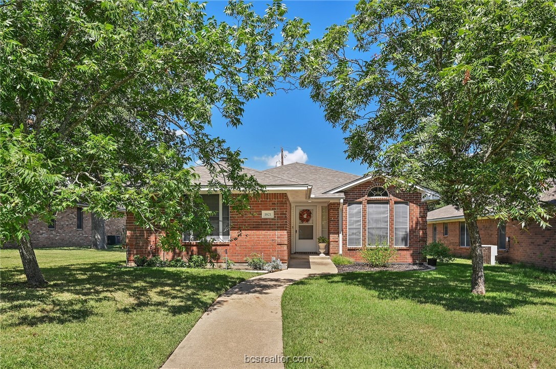 a front view of a house with a garden and tree