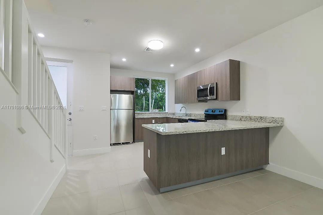 a view of kitchen with stainless steel appliances granite countertop a refrigerator and a stove top oven