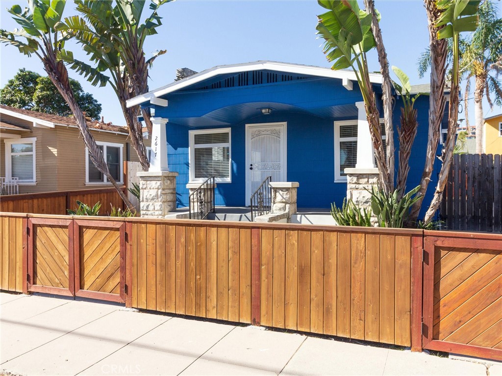 a view of a house with wooden fence and large trees