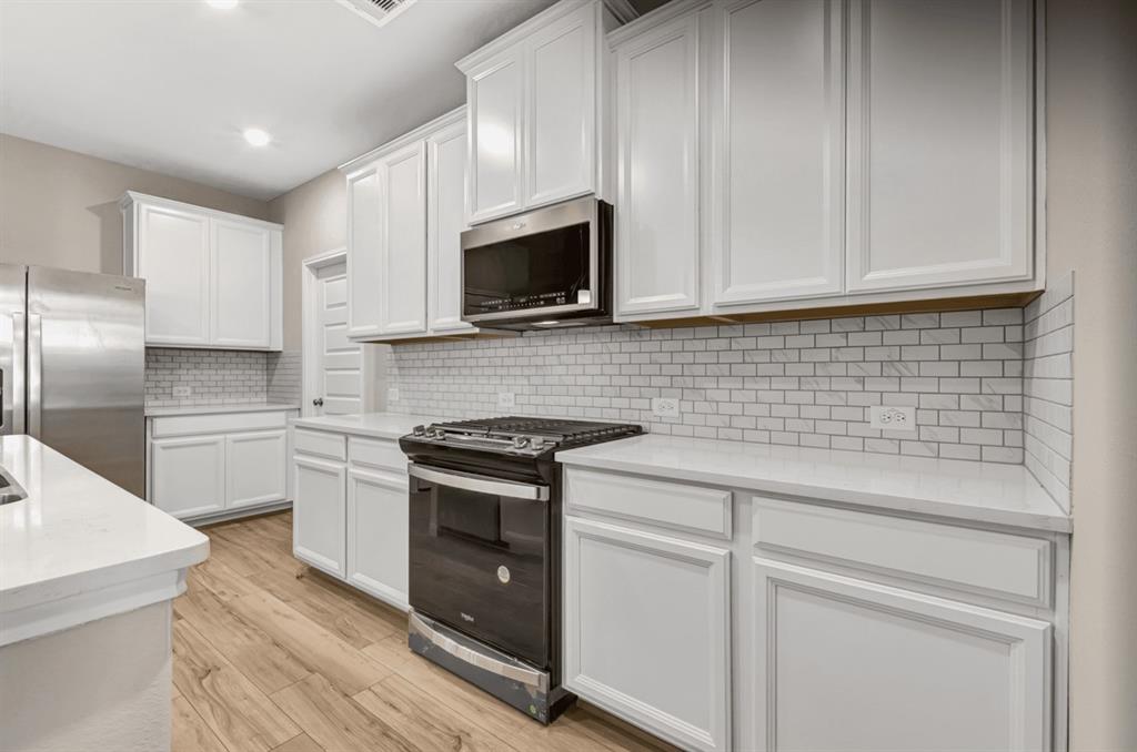 a kitchen with cabinets stainless steel appliances a sink and wooden floor