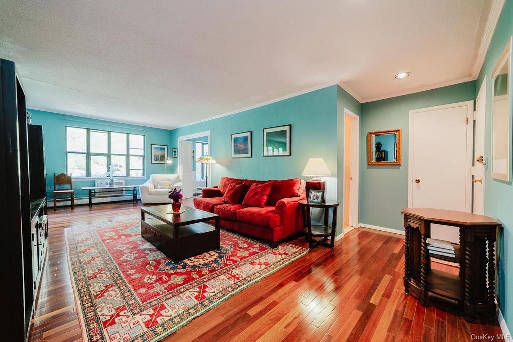 Living room with ornamental molding, hardwood / wood-style flooring, and a baseboard heating unit