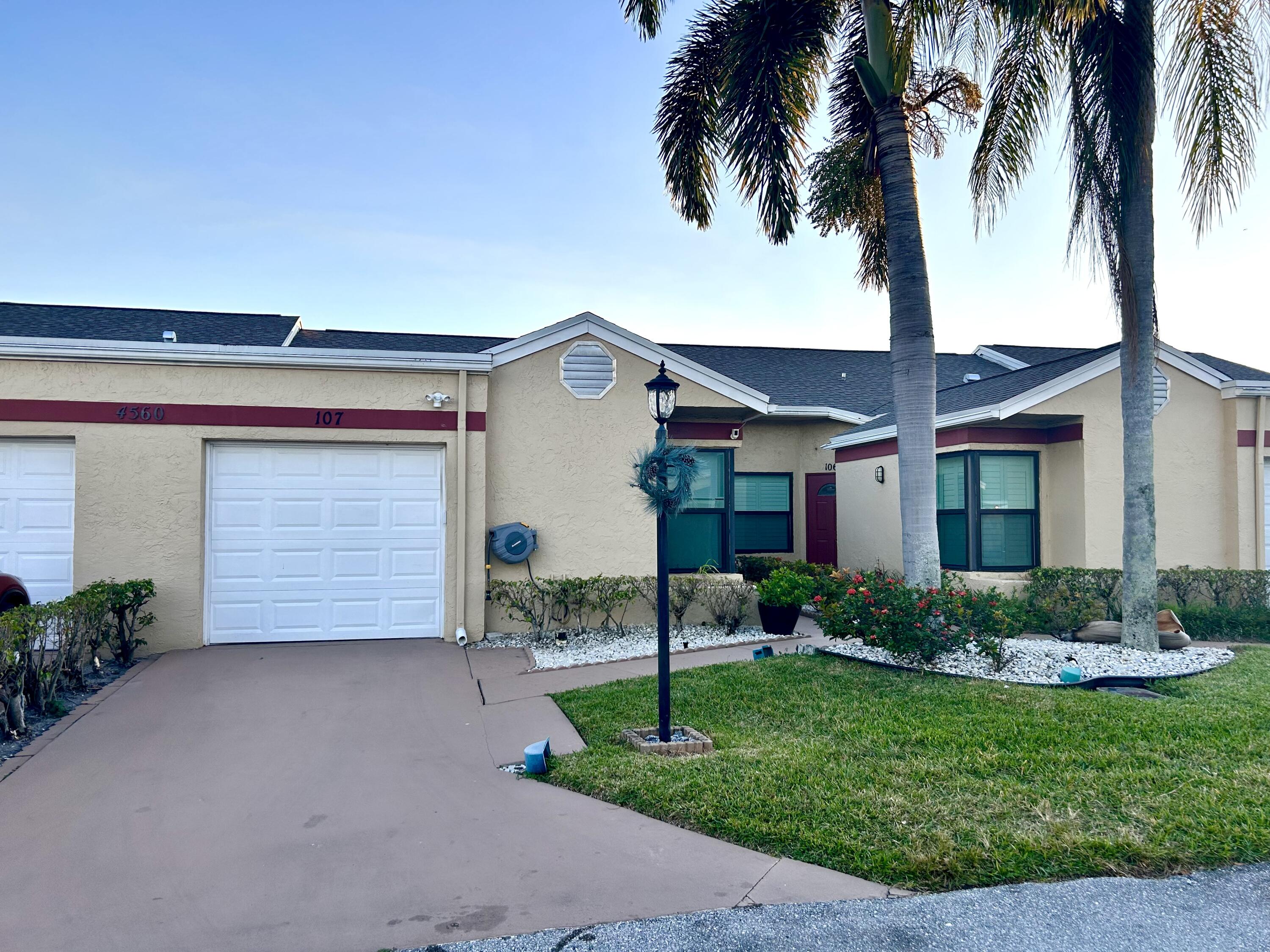 front view of a house with a yard and palm trees