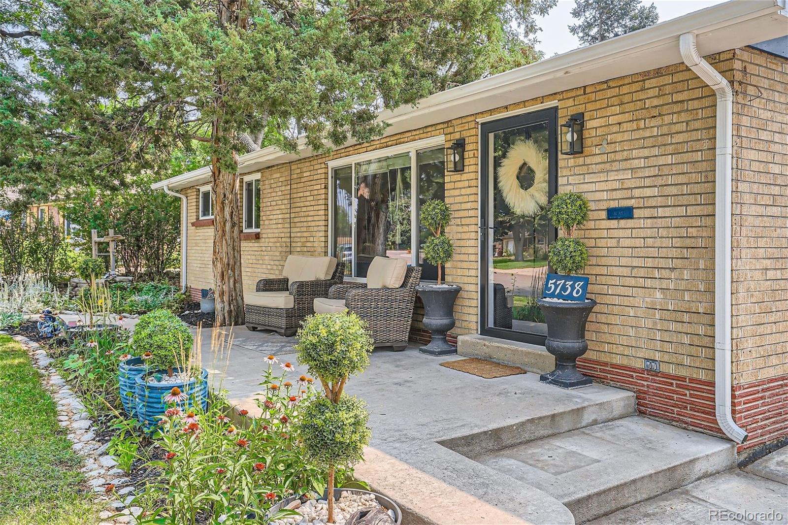 a view of a patio with table and chairs potted plants and large tree