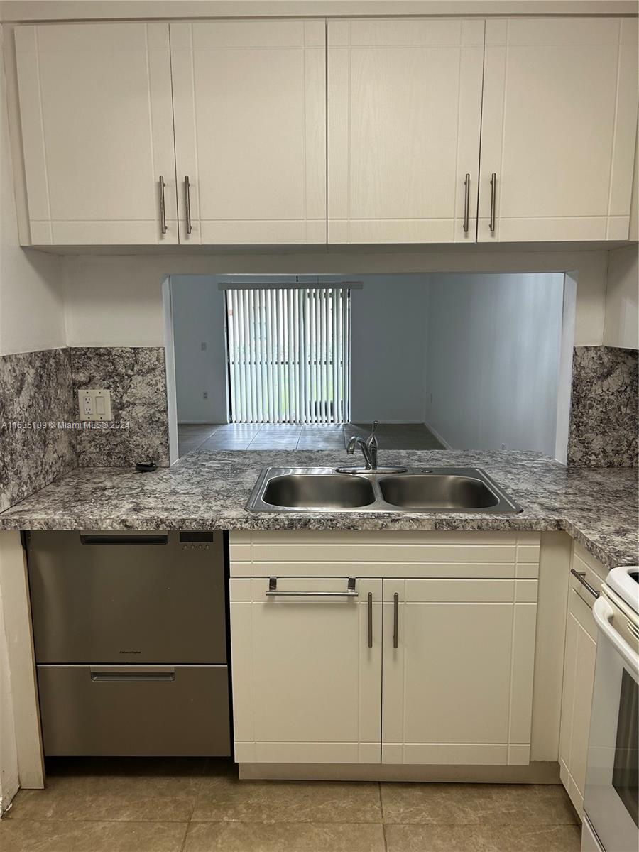 a kitchen with granite countertop a sink and cabinets