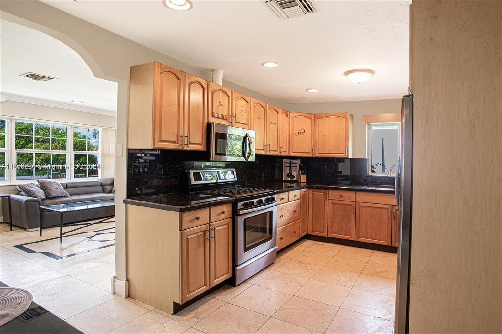 a kitchen with stainless steel appliances granite countertop a stove top oven a sink a dining table and chairs