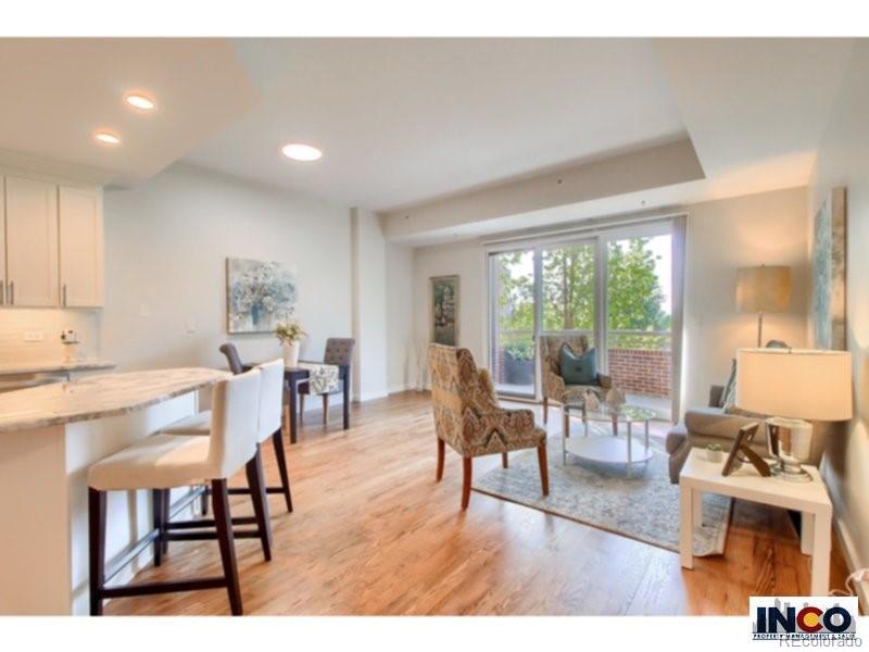 a living room with furniture a wooden floor and a large window