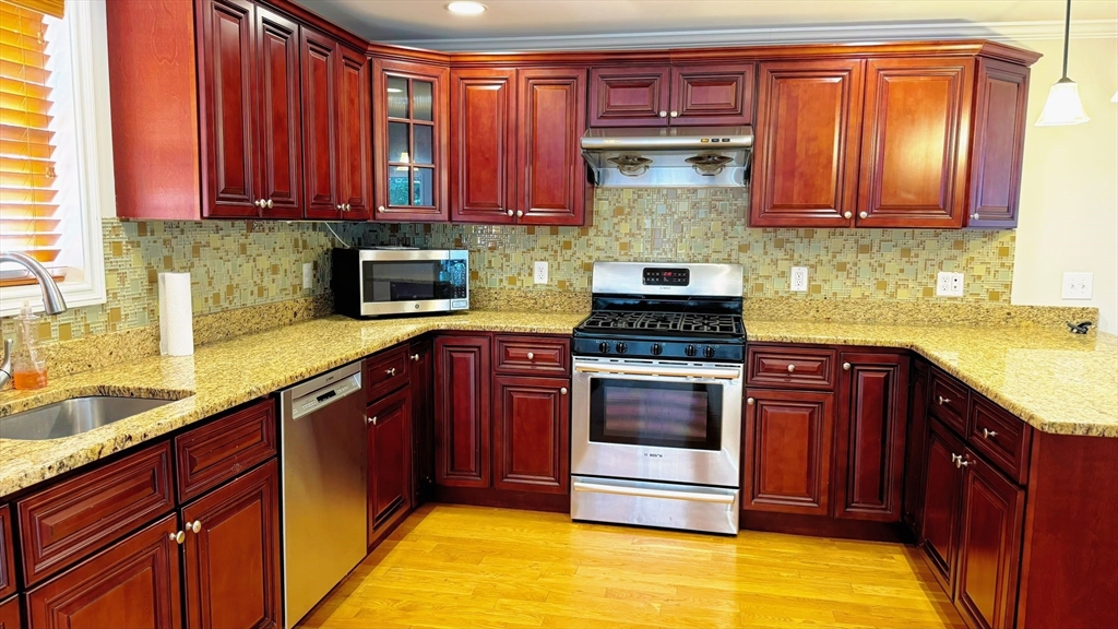 a kitchen with stainless steel appliances granite countertop a stove a sink dishwasher and cabinets with wooden floor