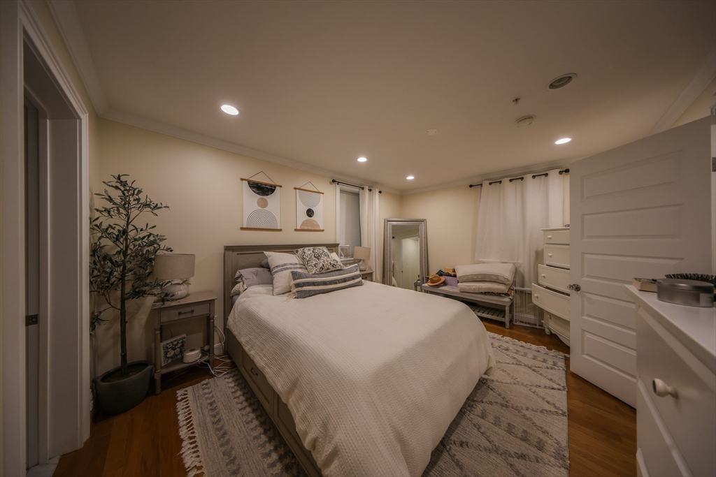 a large bedroom with a bed and a potted plant on the dresser