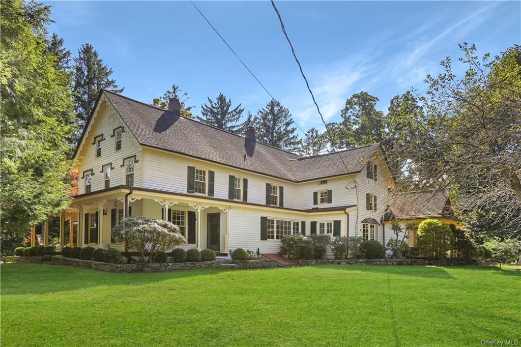 a view of a white house next to a yard with big trees