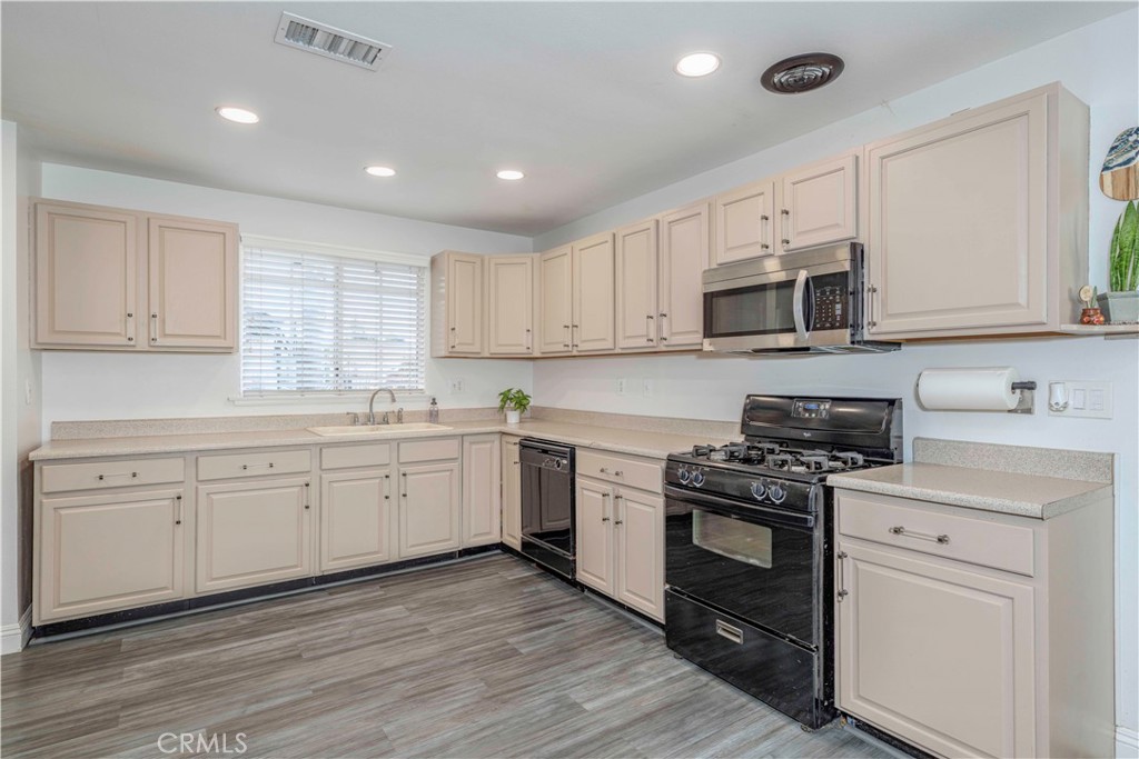 a kitchen with cabinets stainless steel appliances a sink and wooden floor