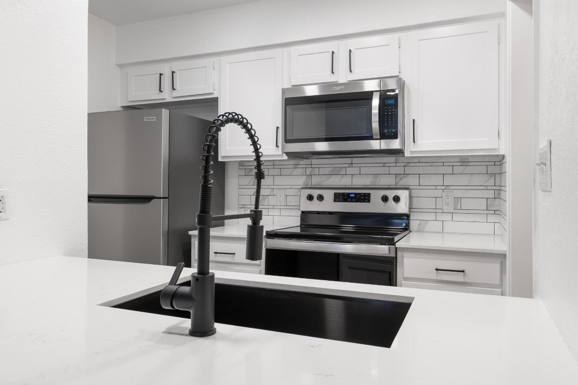 a kitchen with stainless steel appliances a stove microwave and sink