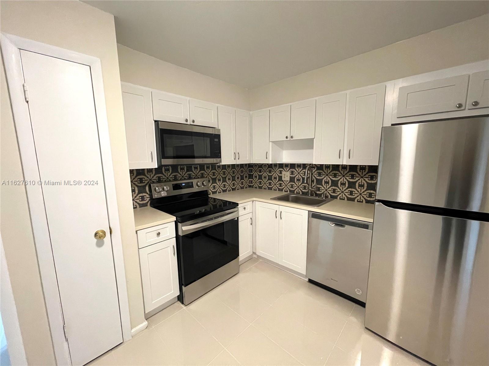 a kitchen with white cabinets and refrigerator