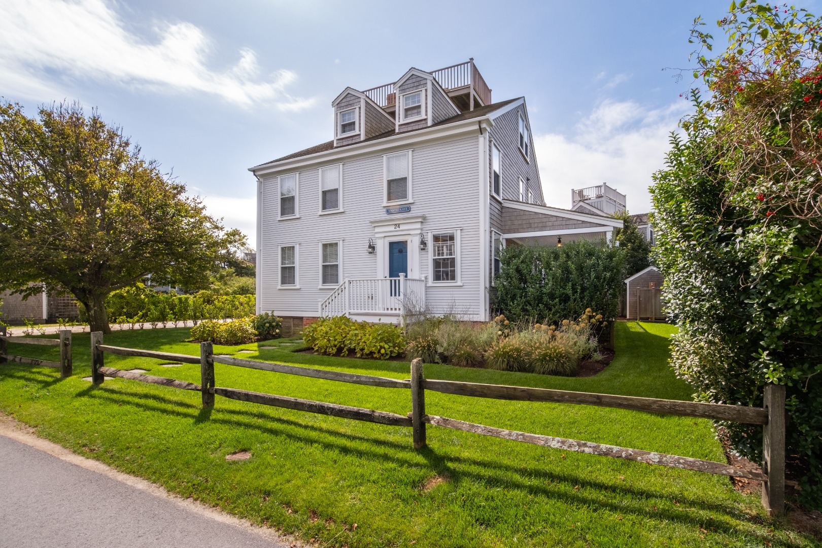 a view of a white house with a big yard and potted plants