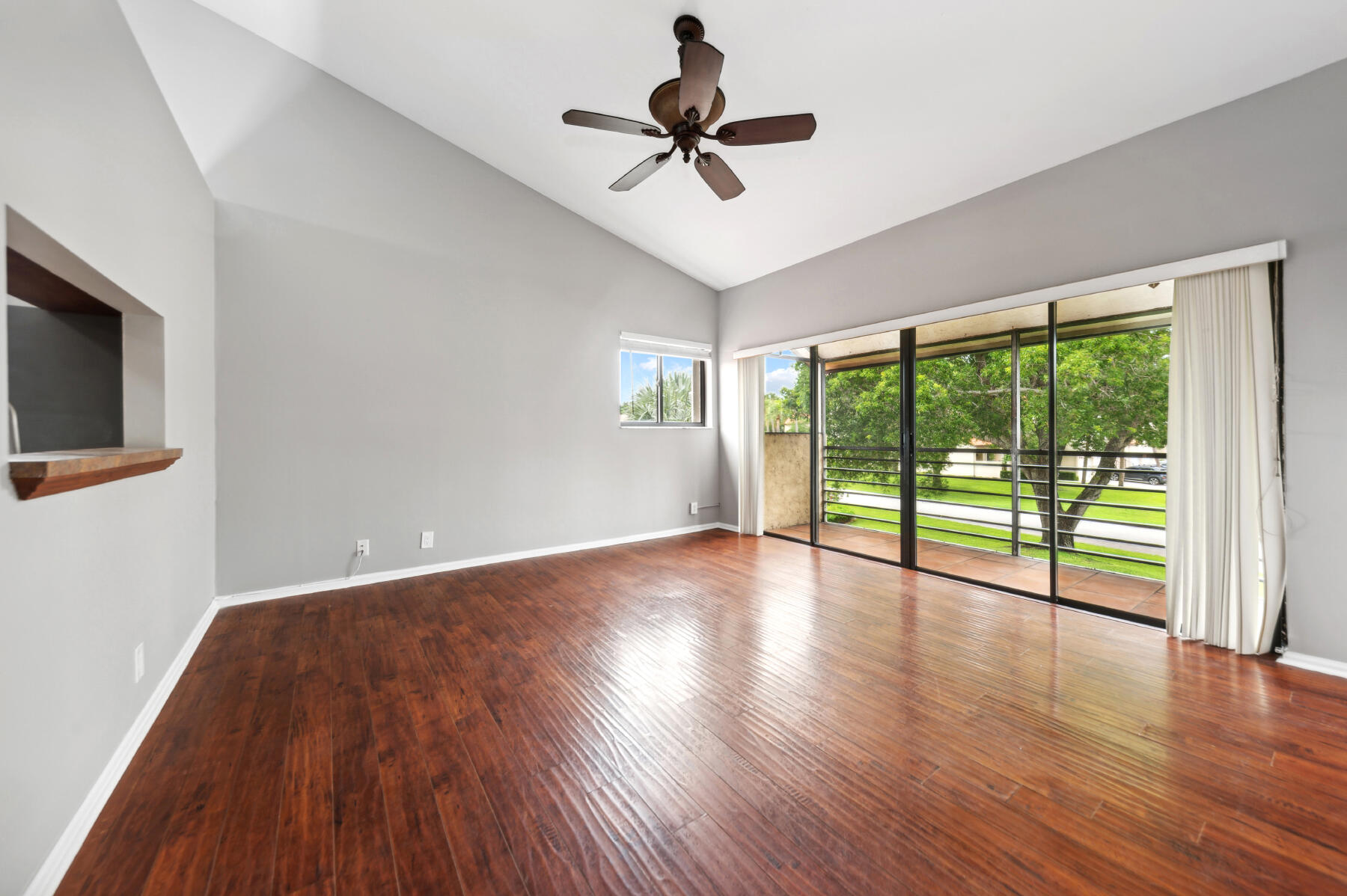 a view of empty room with wooden floor and fan