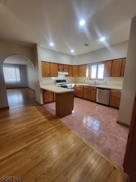 a large room with kitchen island a sink a stove and a wooden floors