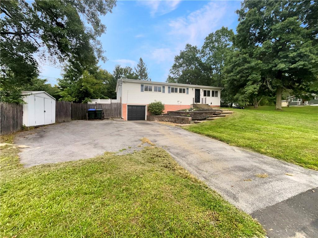 Raised ranch featuring a front lawn and a shed