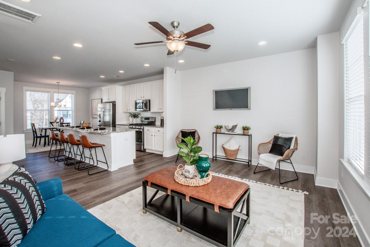 a living room with furniture kitchen view and a wooden floor