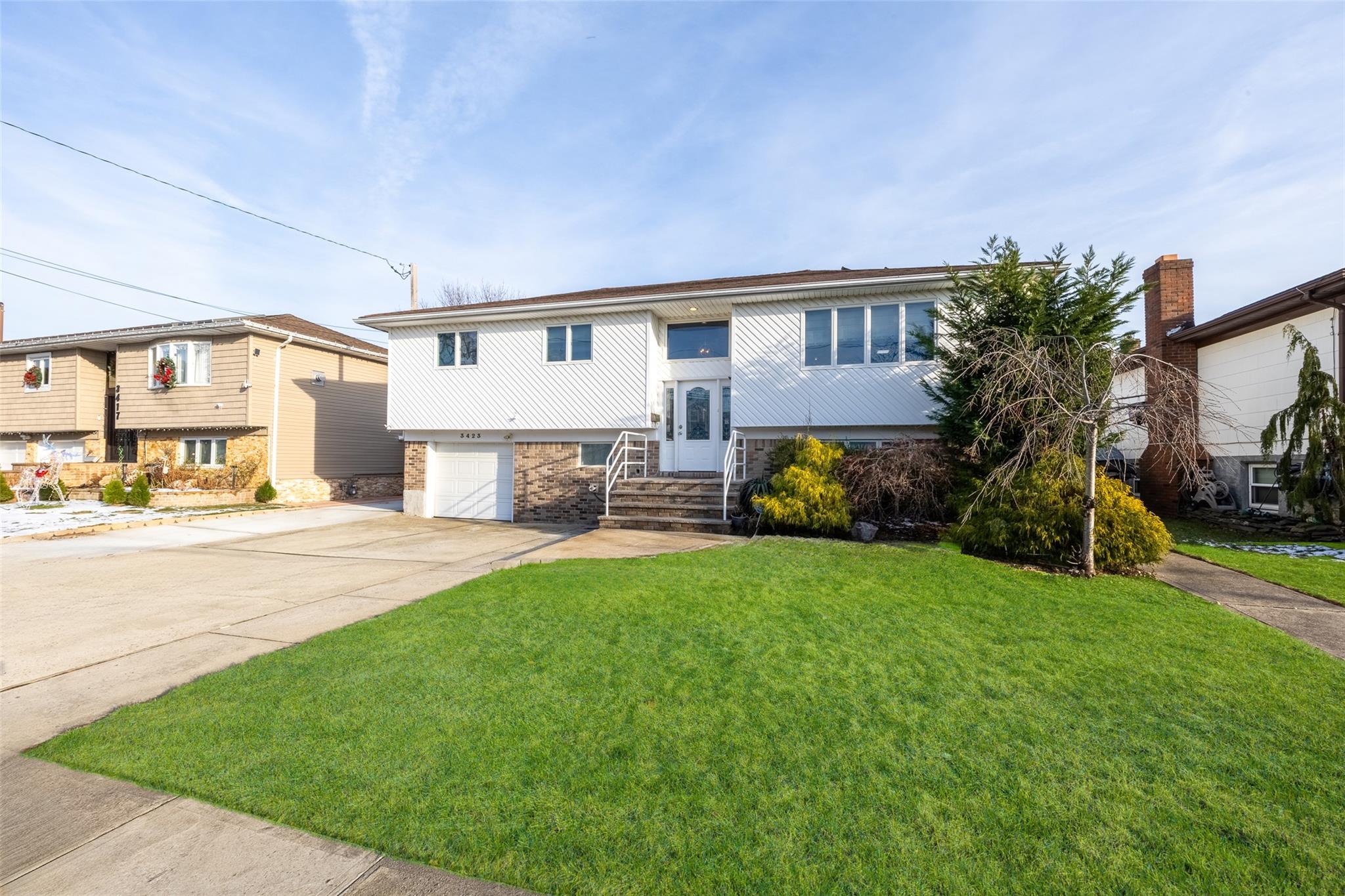 Bi-level home featuring a garage and a front lawn