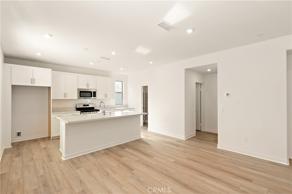 a view of kitchen with stainless steel appliances refrigerator stove microwave and cabinets