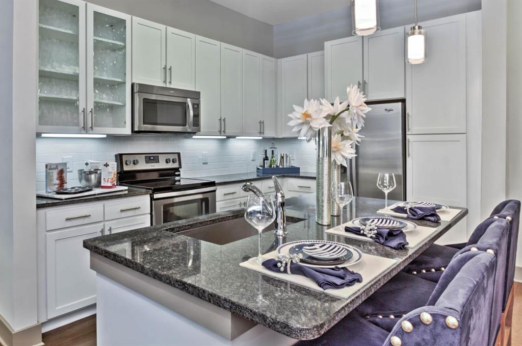 a kitchen with stainless steel appliances granite countertop a sink dishwasher stove and microwave with wooden floor