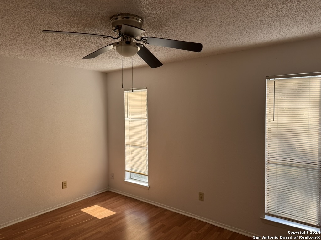 a view of empty room with wooden floor and fan