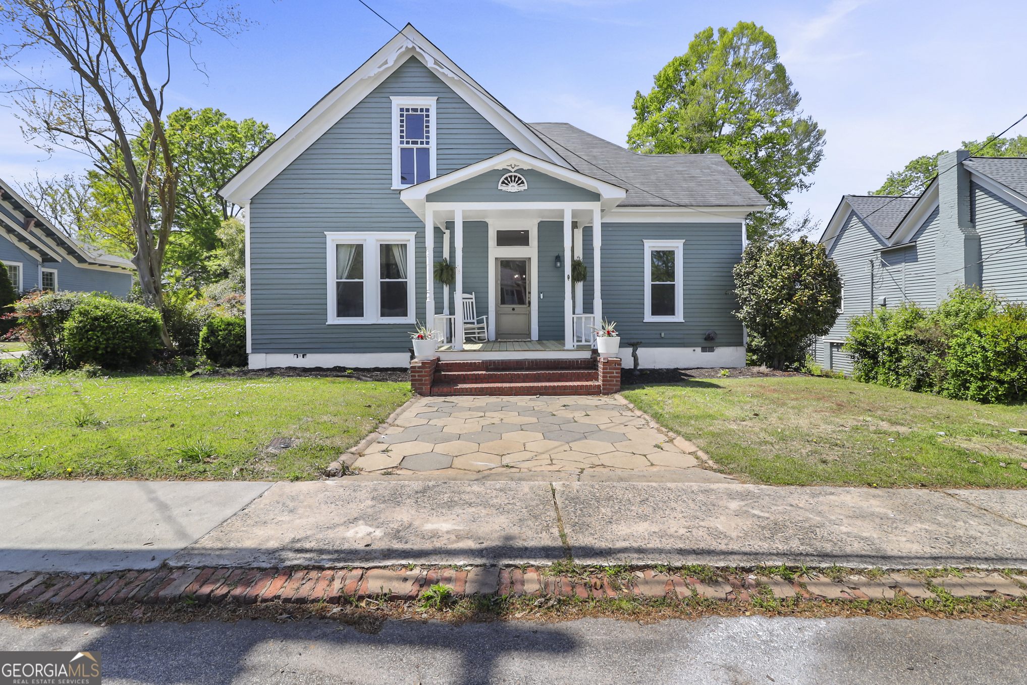 a front view of a house with a yard and potted plants