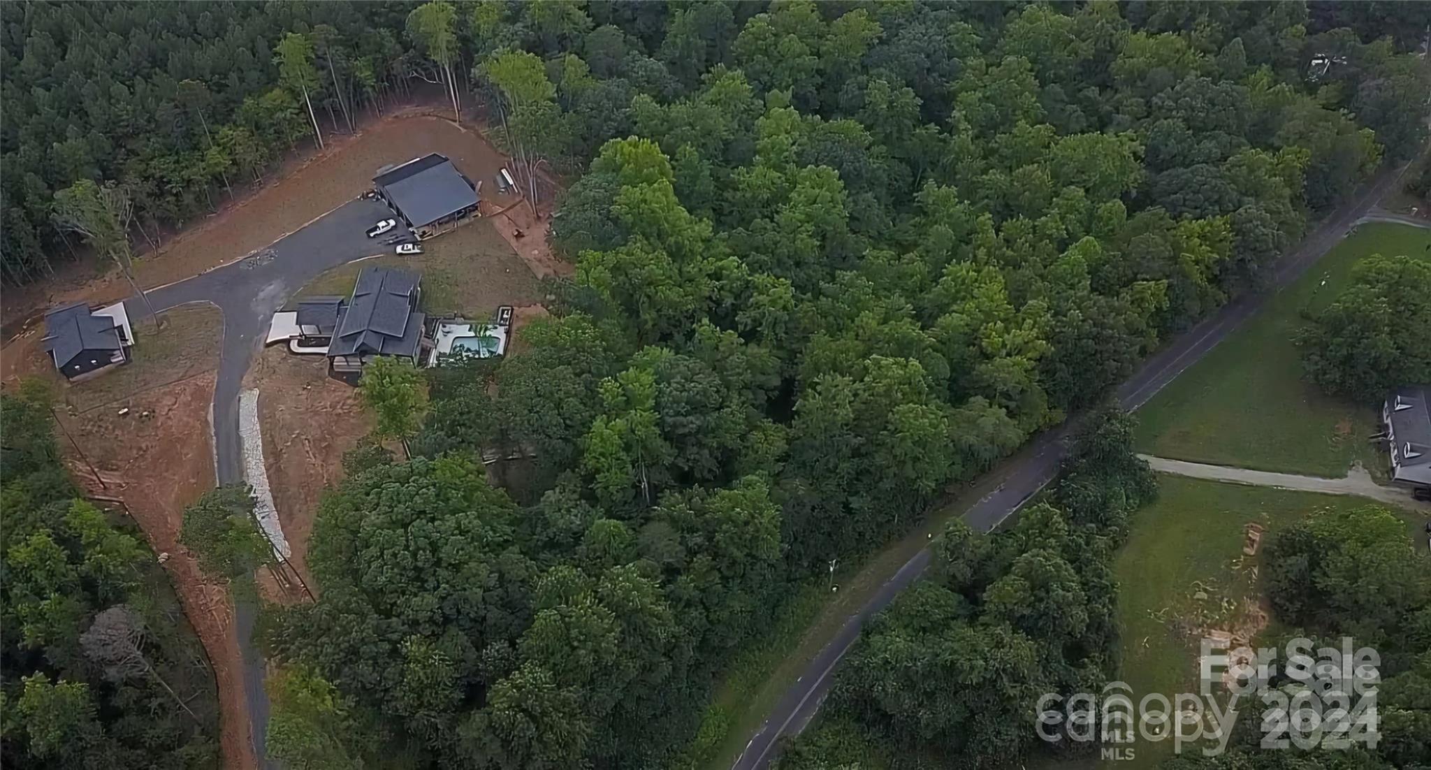 an aerial view of a house with outdoor space and trees all around