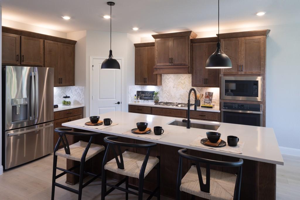 a kitchen with stainless steel appliances a sink a stove a refrigerator and cabinets