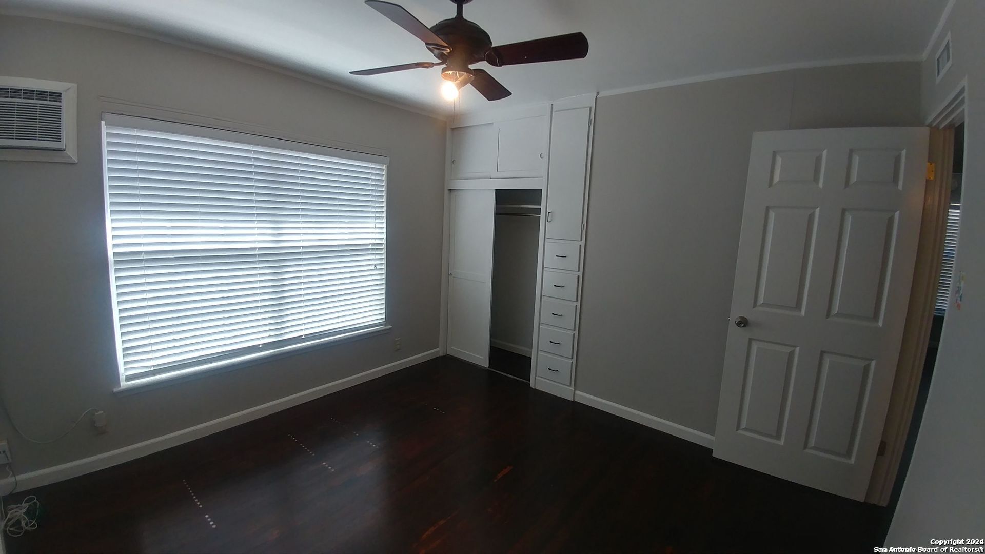 a view of an empty room with wooden floor and a window