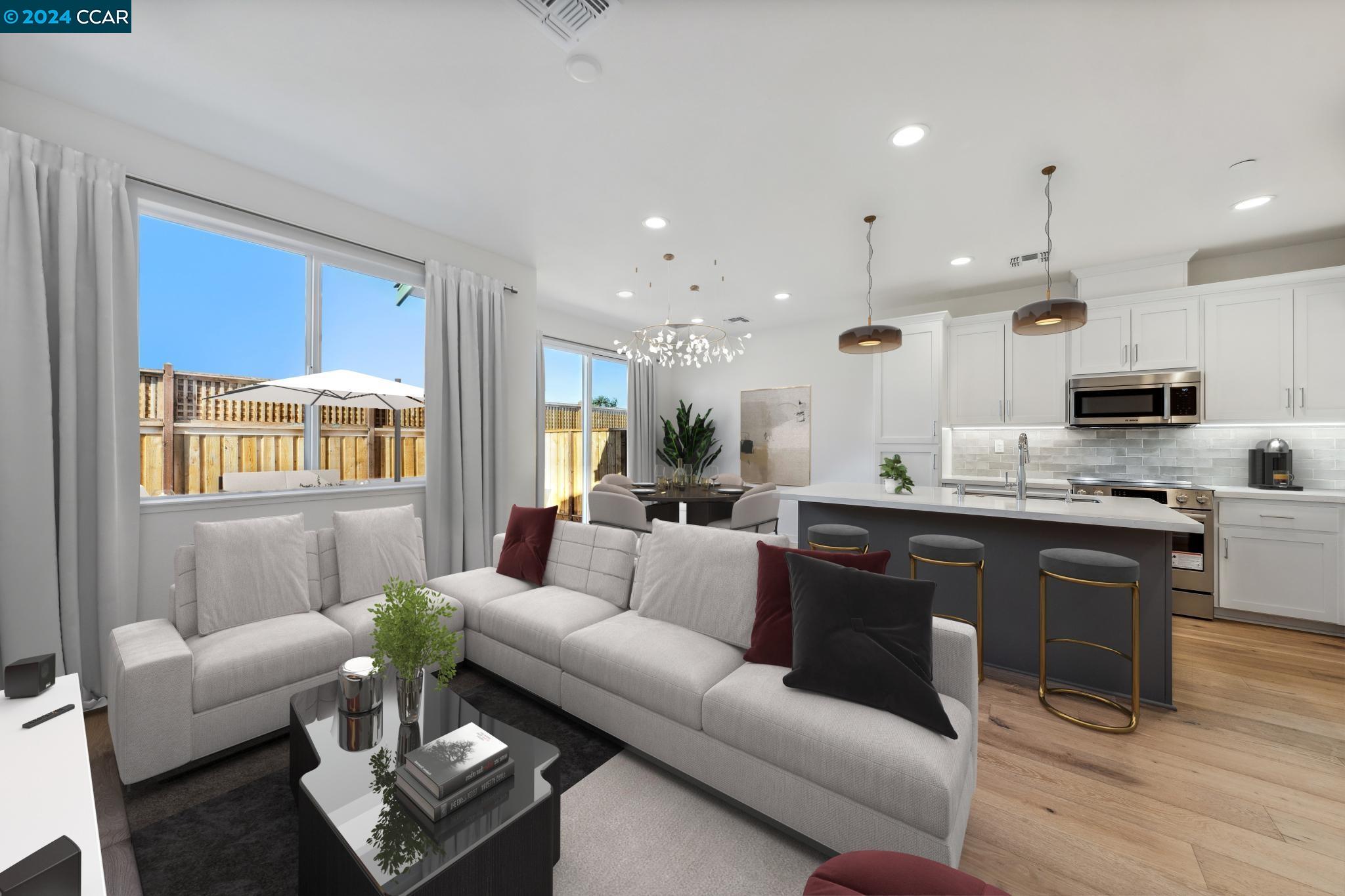 a living room with stainless steel appliances furniture and a kitchen view