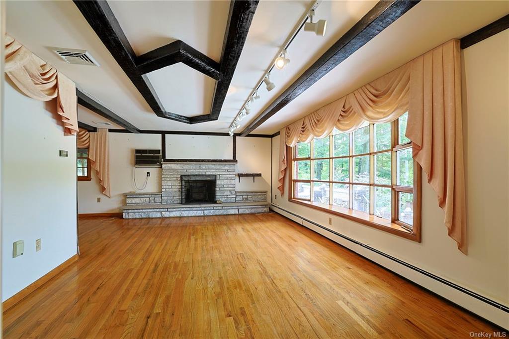 Unfurnished living room with track lighting, hardwood / wood-style floors, baseboard heating, and a fireplace