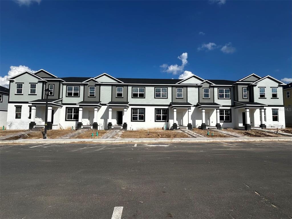 a front view of residential houses with yard and parking