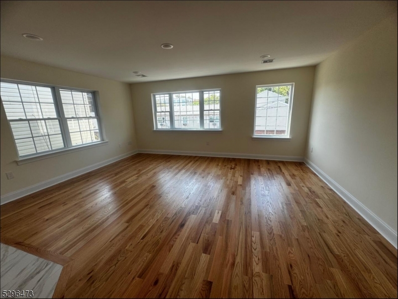 a view of an empty room with wooden floor and window