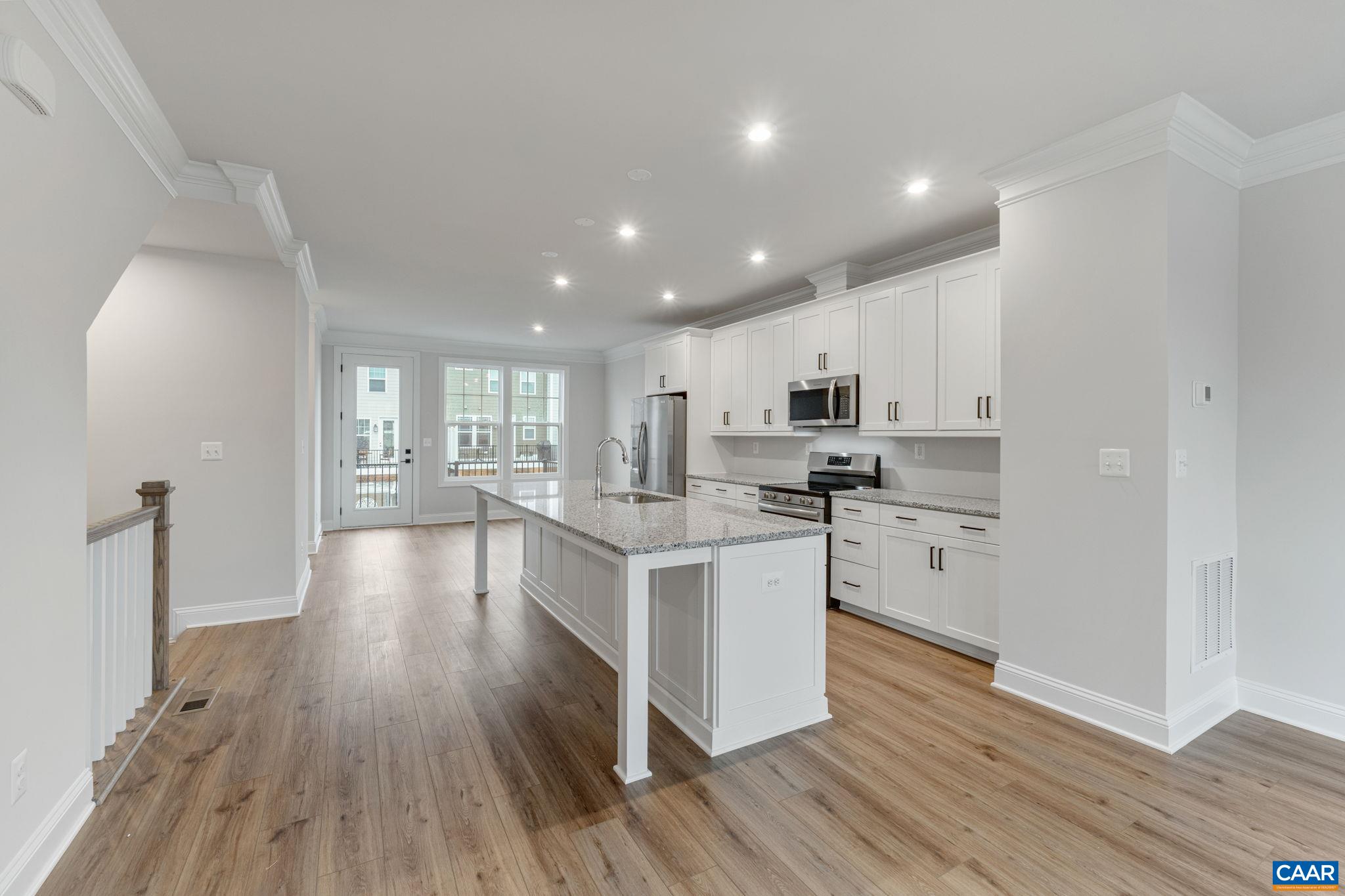 a kitchen with stainless steel appliances granite countertop wooden floors and white cabinets