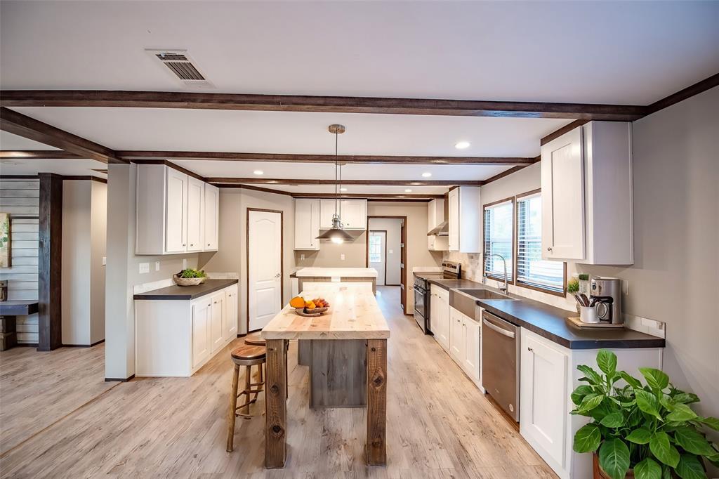 a kitchen with a sink appliances cabinets and wooden floor