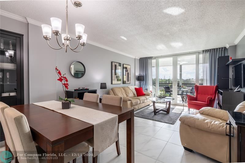 a living room with couches a dining table and a chandelier with kitchen view