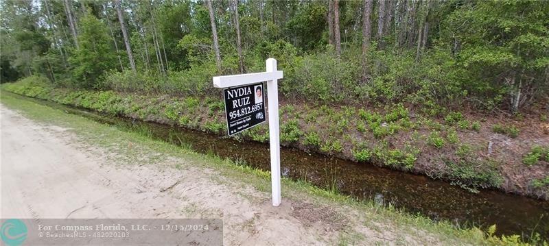 a sign that is sitting in front of a tree